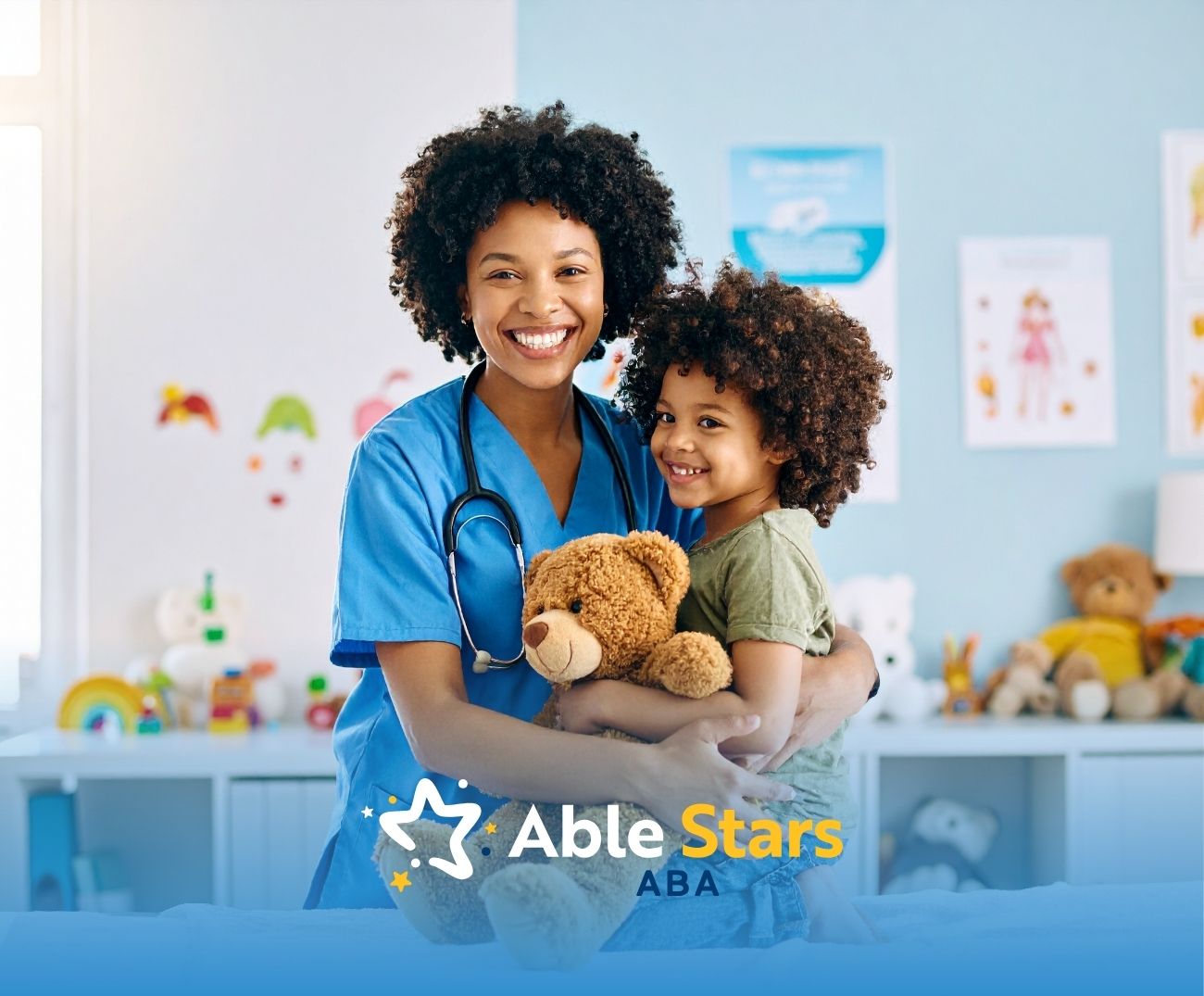 Smiling healthcare worker in blue scrubs hugs a child holding a teddy bear. They stand in a colorful, cheerful room, radiating warmth and care.