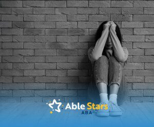 A person sits against a brick wall, head buried in hands, conveying distress.